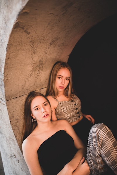 Sister act, KTJ & Carly, sitting inside of an art structure.